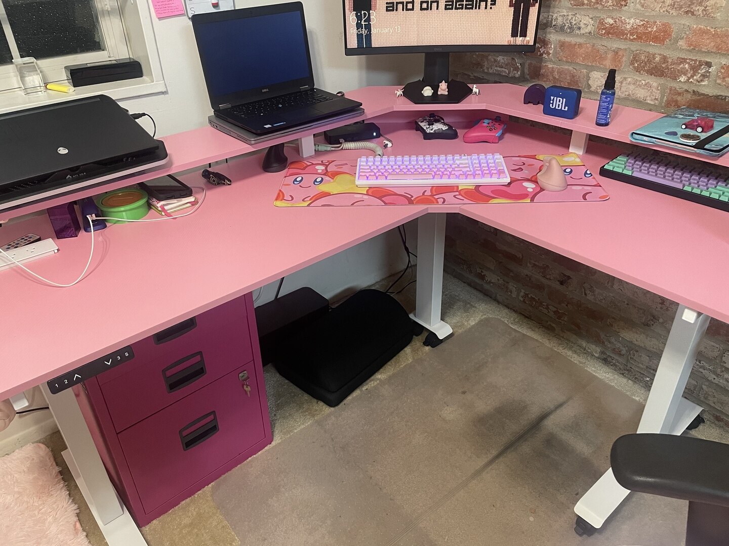 Image showing a pink corner desk with under-desk storage and lighting, used for gaming or computer work.